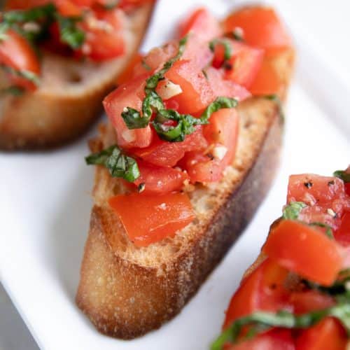 Bruschetta recipe topped with olive oil topped with tomatoes, garlic, and basil.