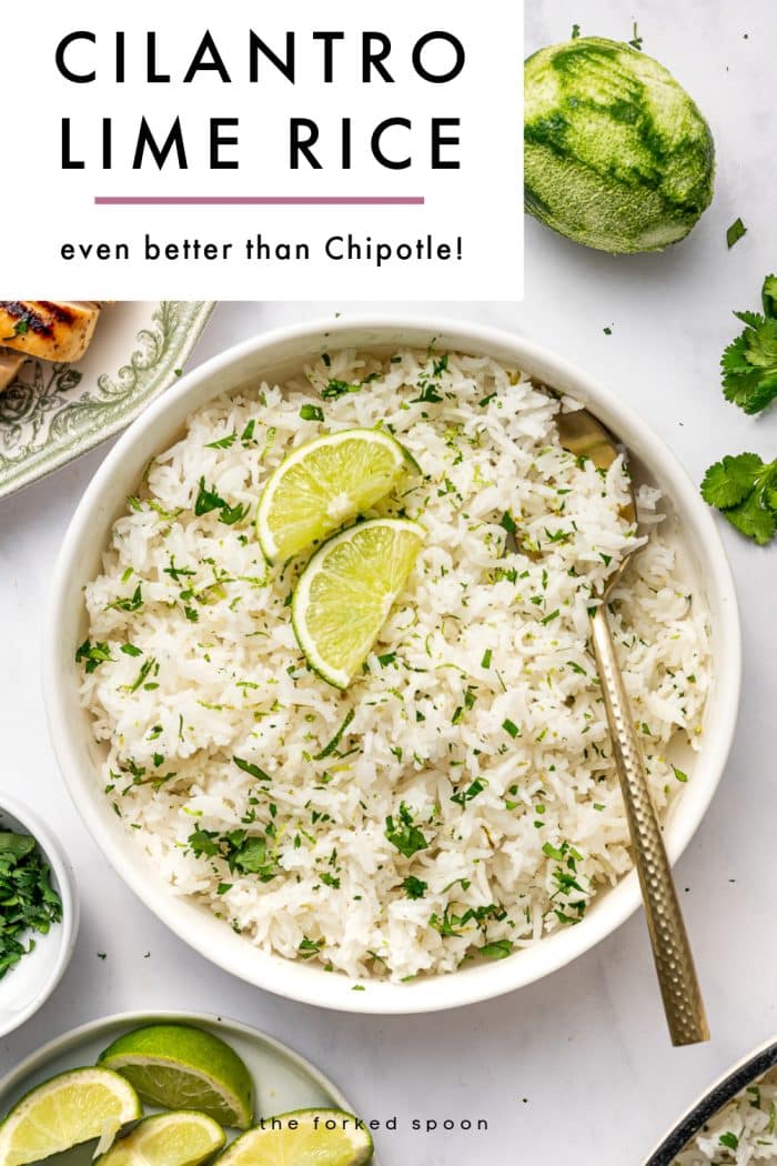 Vertical Pinterest graphic for cilantro lime rice on a light gray marble background. A large white text box in the upper left corner reads “CILANTRO LIME RICE” in bold black uppercase letters, with a thin pink line underneath and the subtitle “even better than Chipotle!” below. The main image shows a round white bowl filled with fluffy white cilantro lime rice garnished with two lime wedges and chopped green cilantro, with a gold spoon resting in the bowl. Around the bowl are a small white bowl of chopped cilantro, a plate of lime wedges, fresh cilantro sprigs, part of a green patterned plate with sliced grilled chicken, a whole zested lime, and the edge of a cream-colored pot. The words “the forked spoon” appear at the bottom.