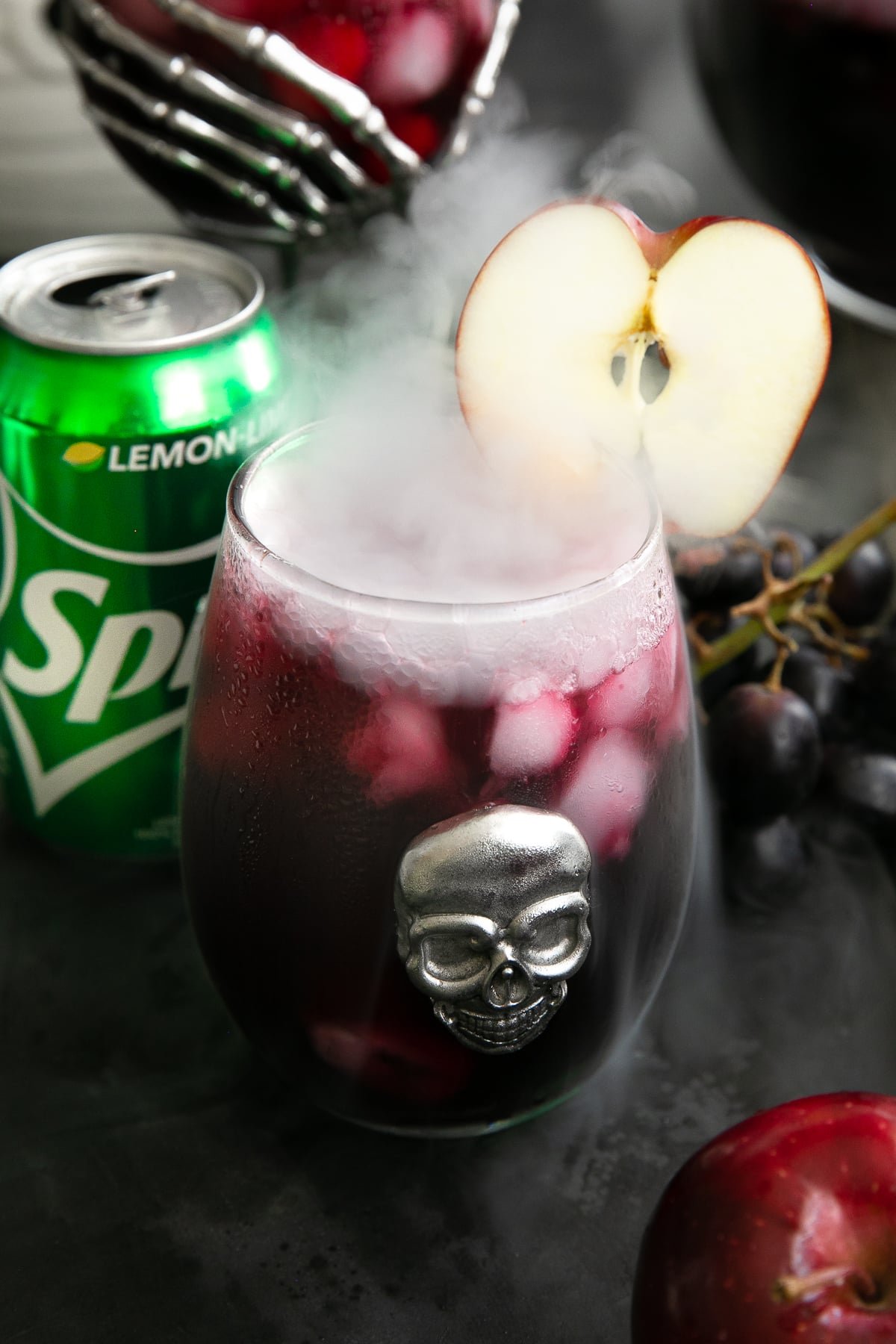 Bubbling and smoking glass of red sangria garnished with a sliced apple.