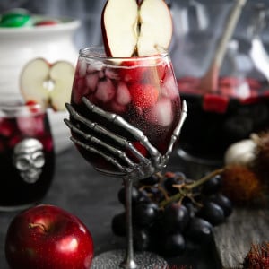 Large skeleton hand wine goblet filled with red sangria made with raspberries, blackberries, apples, and Sprite.