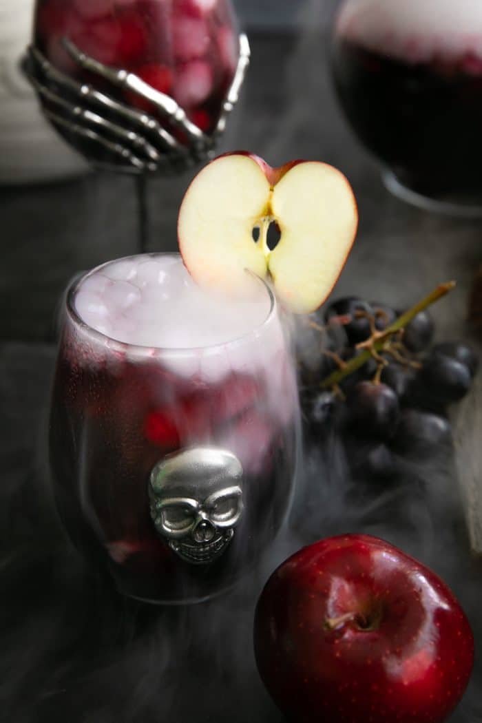 Stemless wine glass filled with red sangria and bubbling from dry ice.