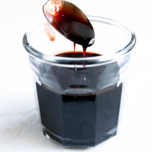 Glass jar filled with syrupy pomegranate molasses.l
