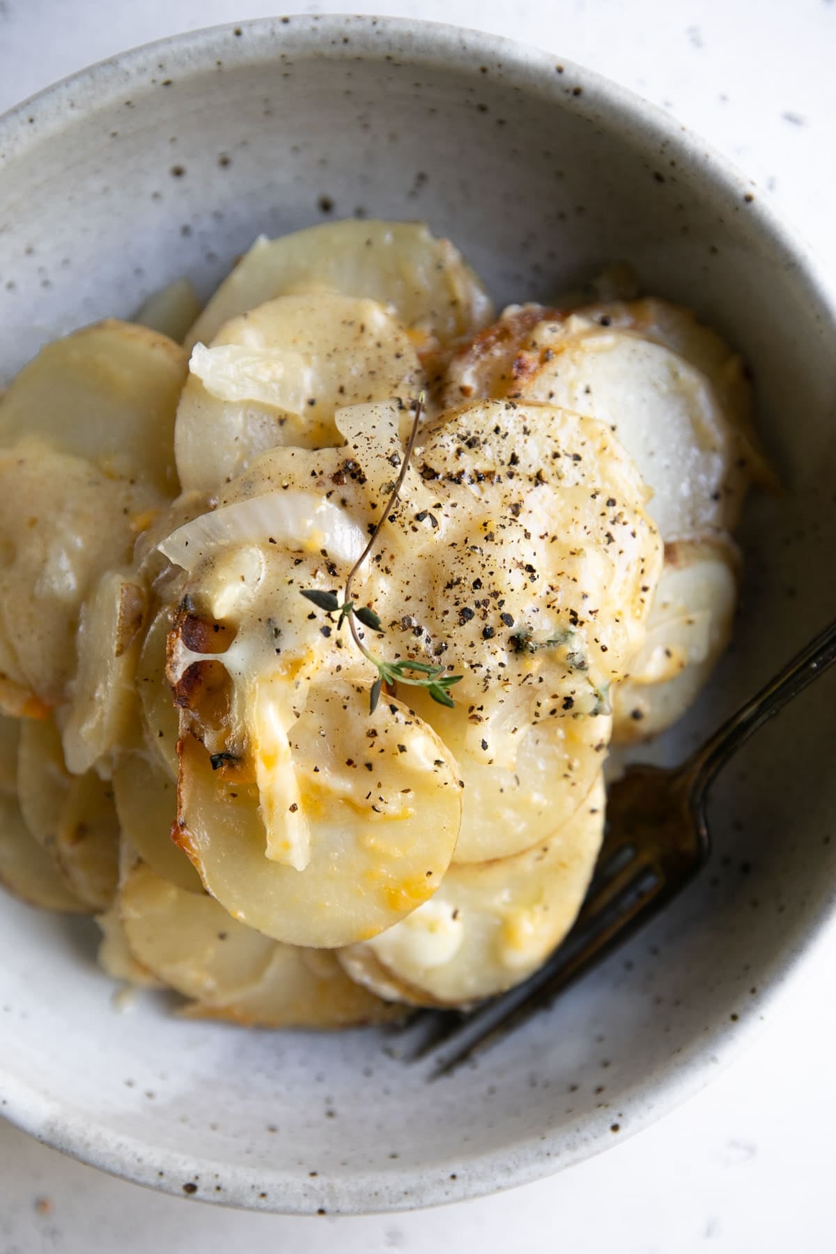 Bowl filled with thinly sliced potatoes au gratin.