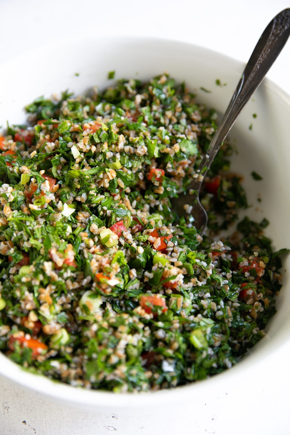 Large white serving bowl filled with bulgur tabbouleh salad.