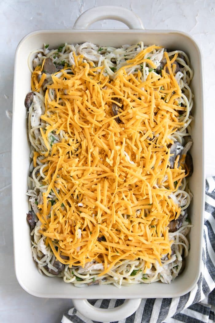 Casserole dish filled with noodles and chicken in a homemade cream sauce and topped with shredded cheese.