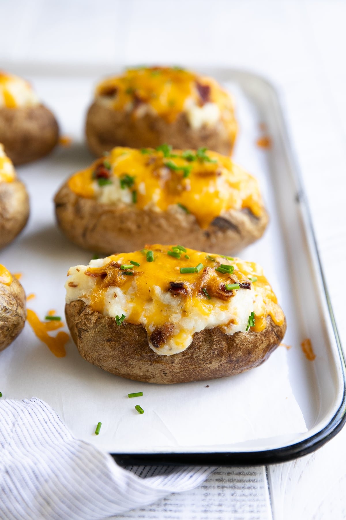 Twice baked potatoes topped with melted cheddar cheese, bacon bits, and fresh chives.