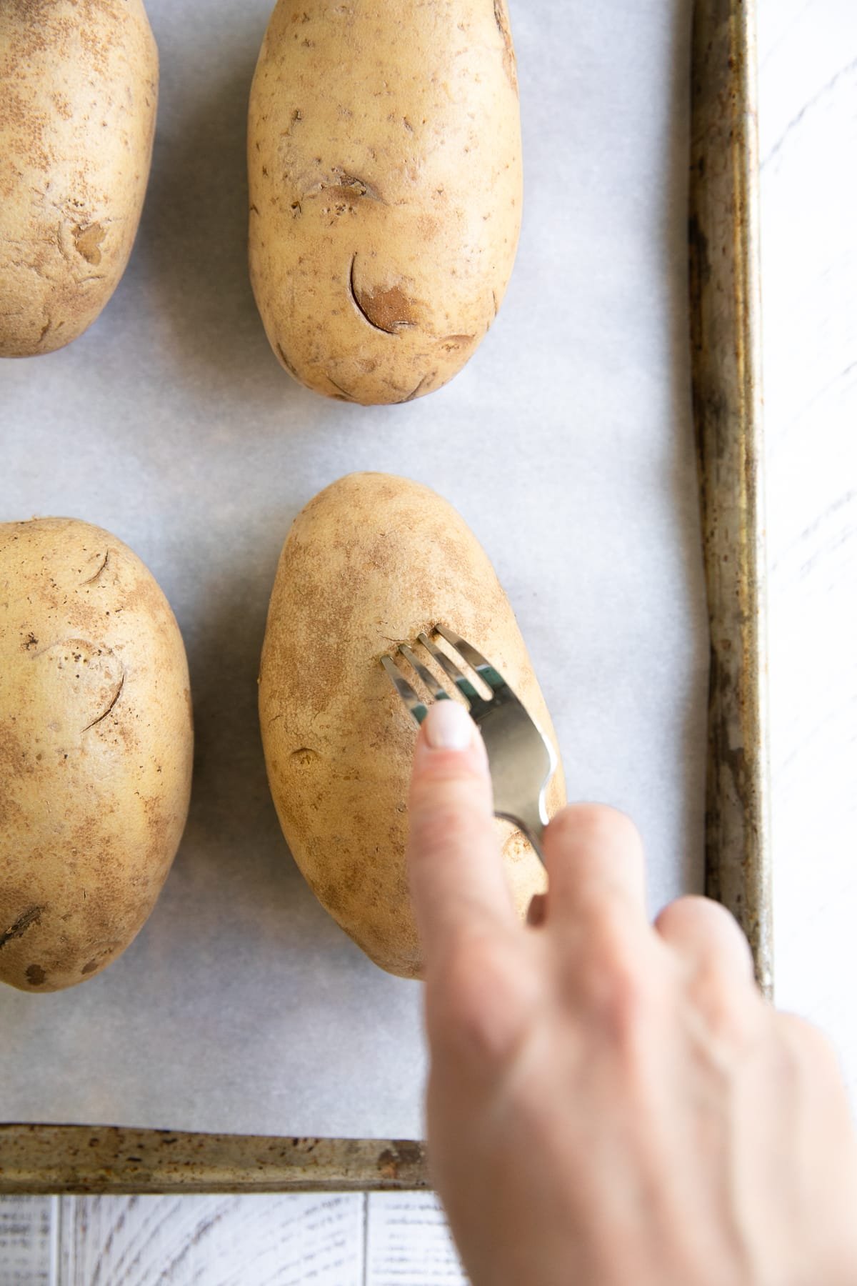 Russet potato being poked with a fork.