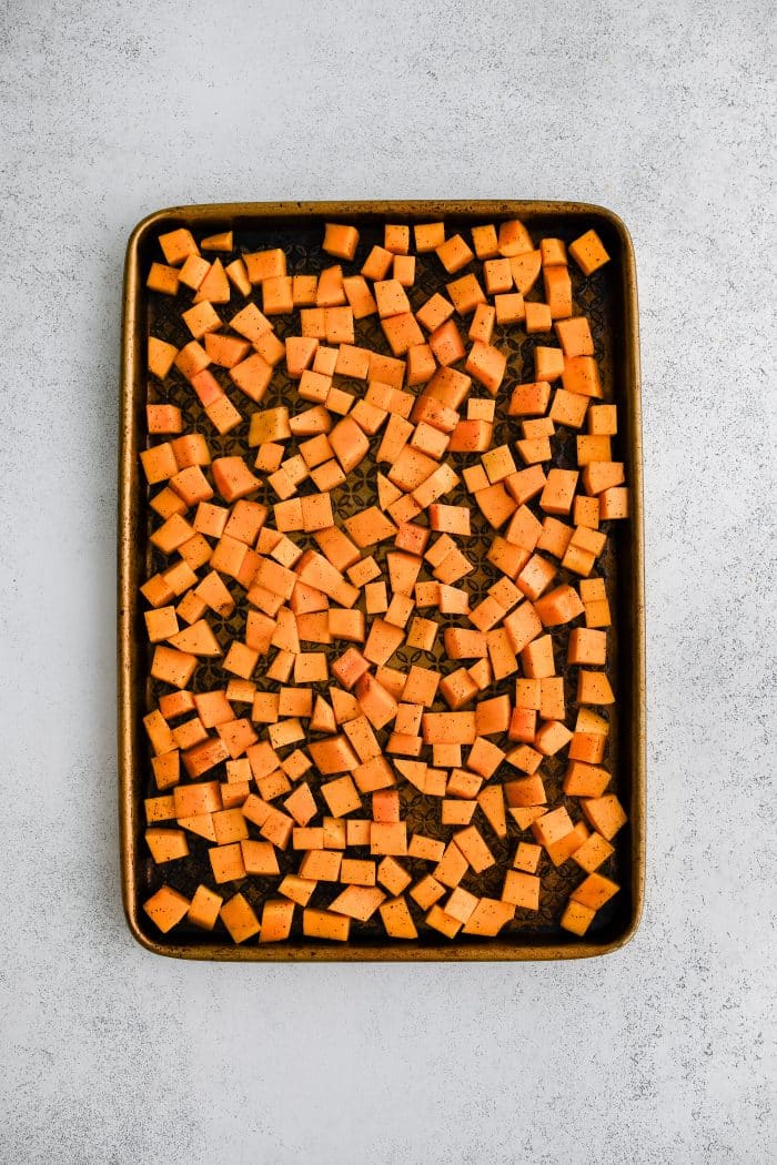 Large rimmed baking sheet withcubes of butternut squash.