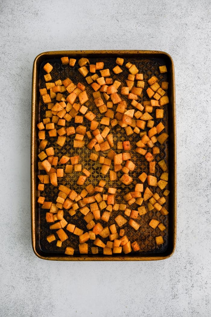 Large rimmed baking sheet with roasted cubes of butternut squash.