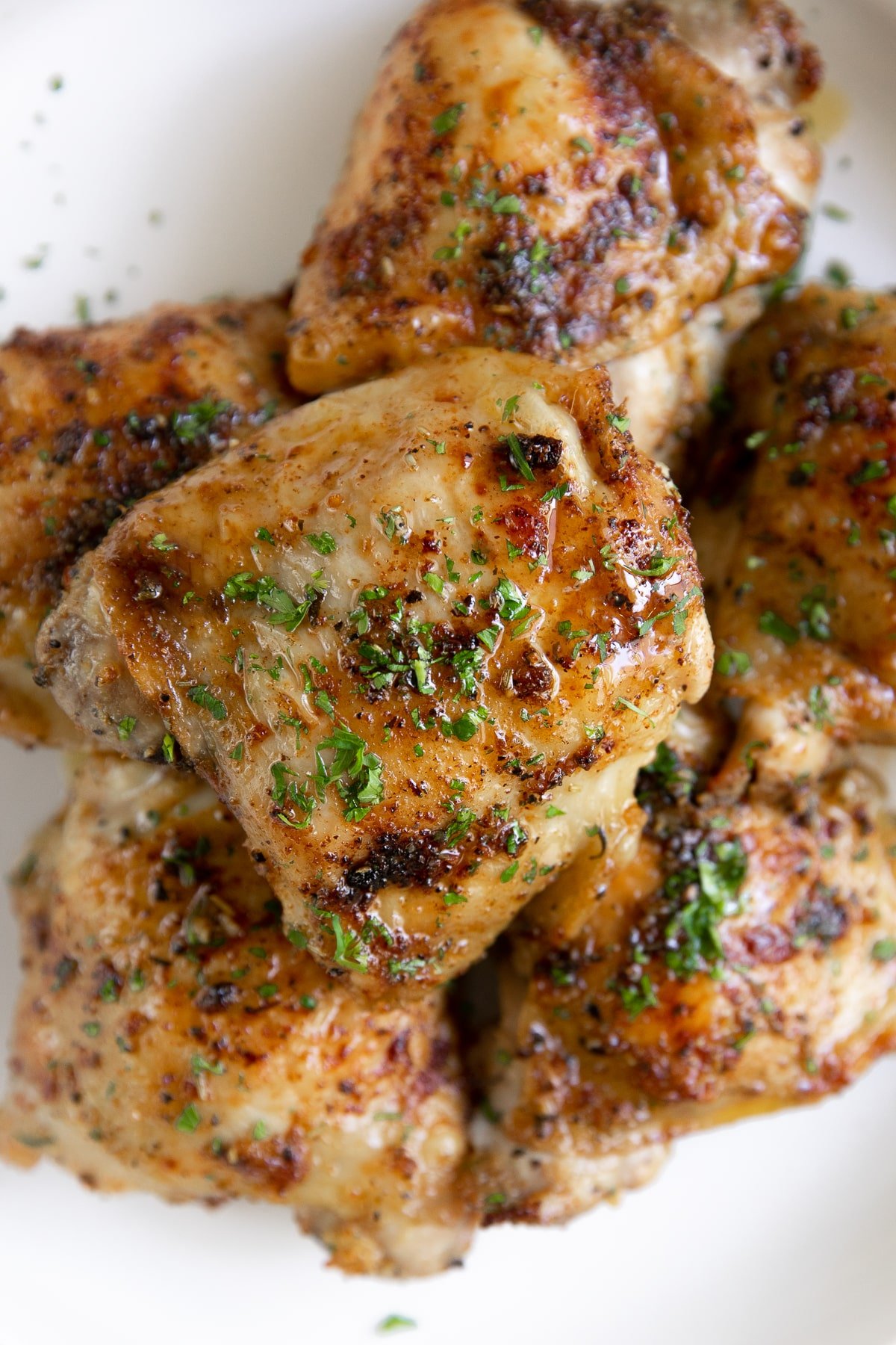 Plate filled with a pile of baked chicken thighs.