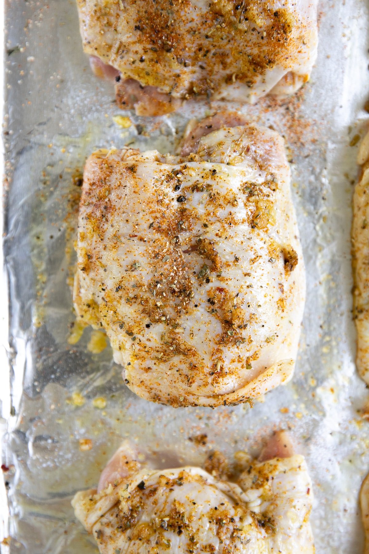 Six bone-in skin-on chicken thighs drizzled with olive oil, smothered with minced garlic and seasoned with Italian seasoning, salt, pepper, and paprika.