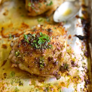 Baked chicken thighs garnished with fresh chopped parsley.