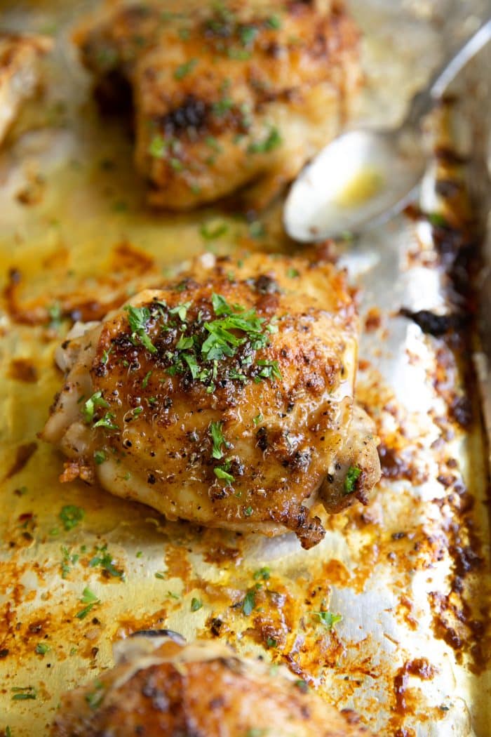 Baked chicken thighs garnished with fresh chopped parsley.
