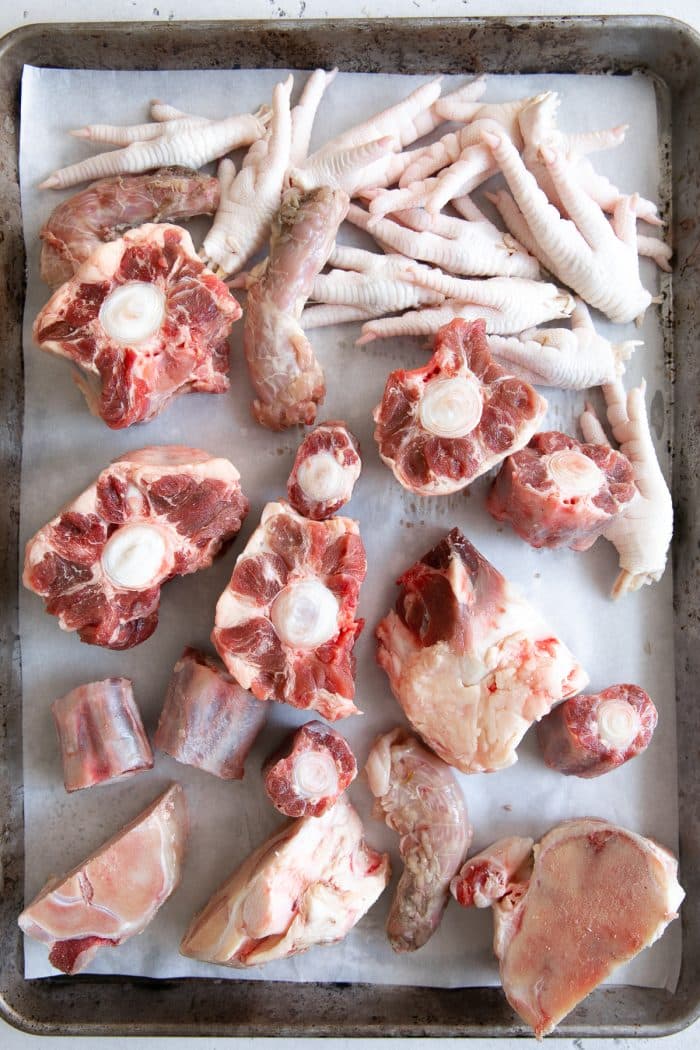 Beef bones and chicken feel on a large baking sheet.