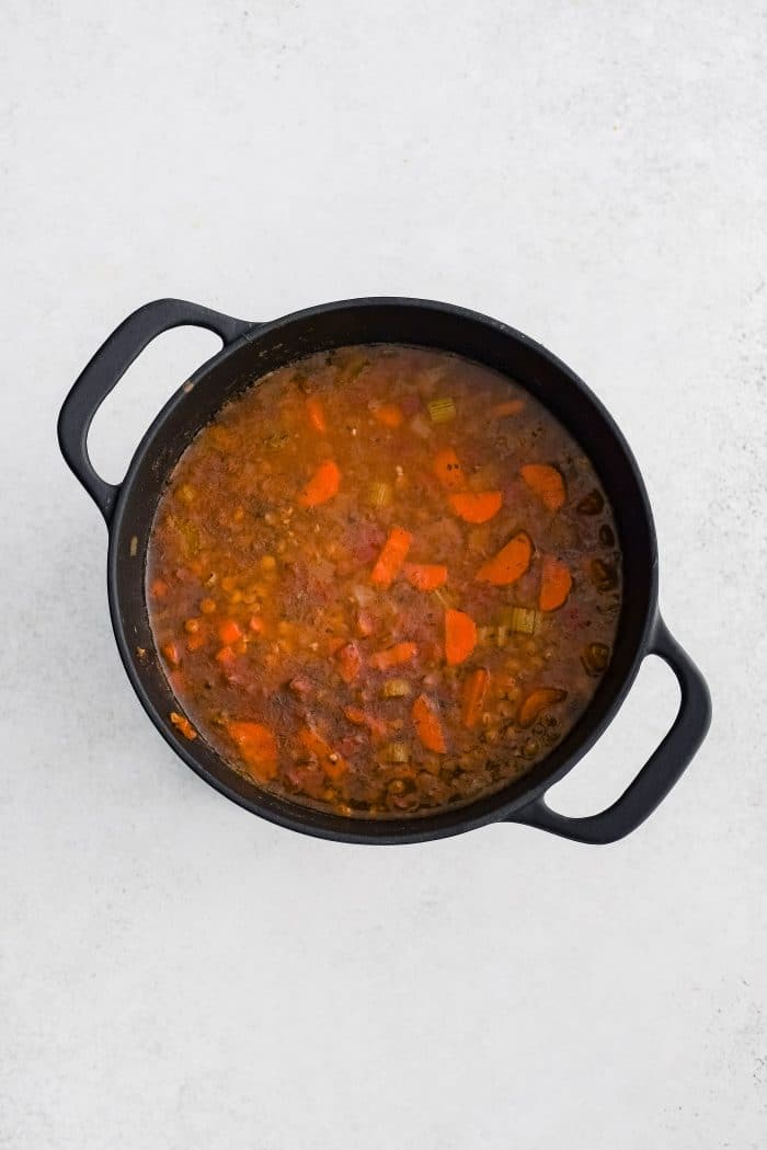 Simmering lentil soup in a large cast iron pot.