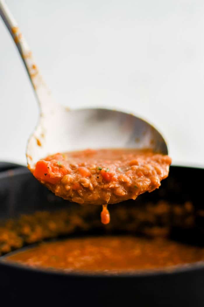 Scoop of lentil soup in a large metal ladle.