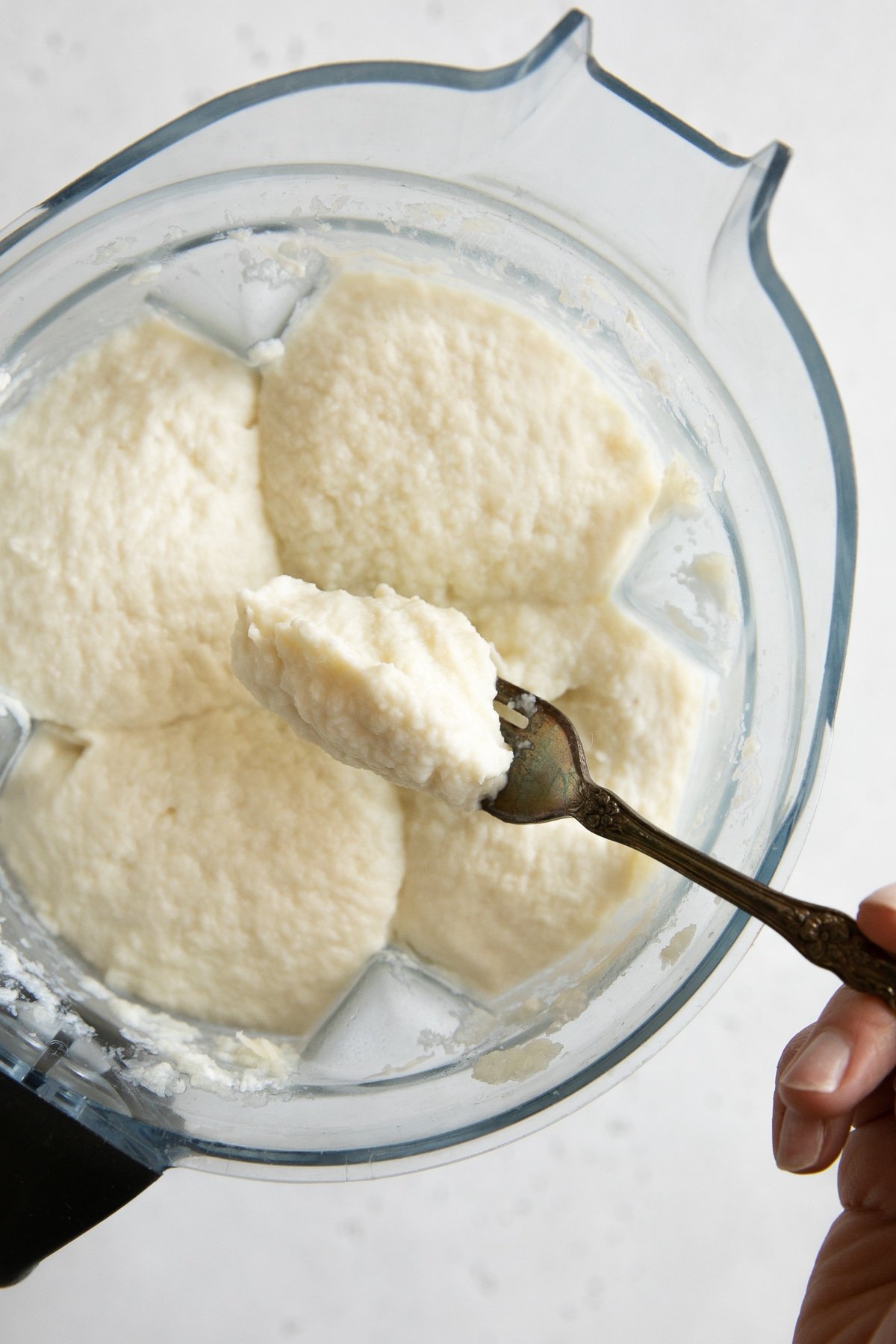 Fork full of creamy mashed cauliflower in a large blender.