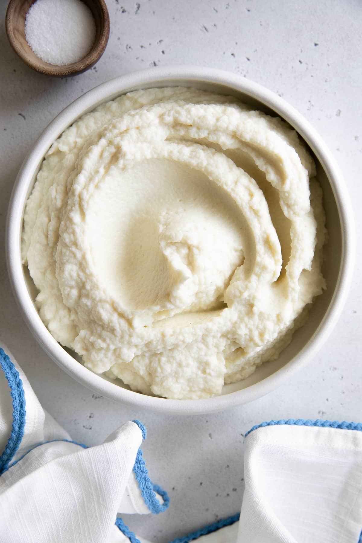 White serving bowl filled with creamy cauliflower mashed potatoes.