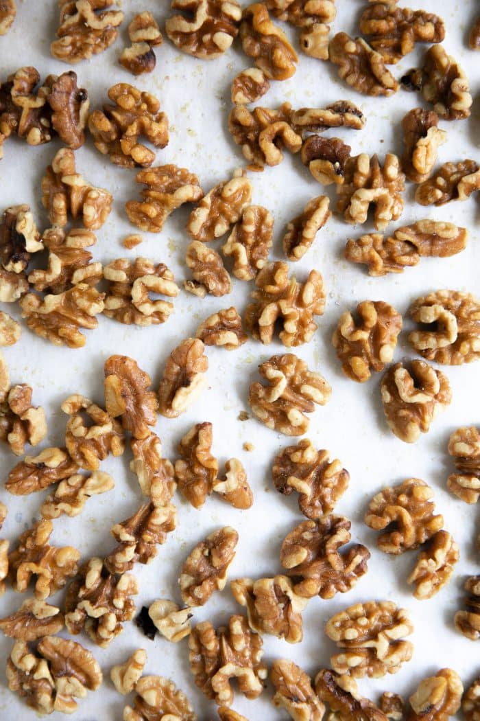 Lightly roasted whole walnuts on a large baking sheet lined with parchment paper.