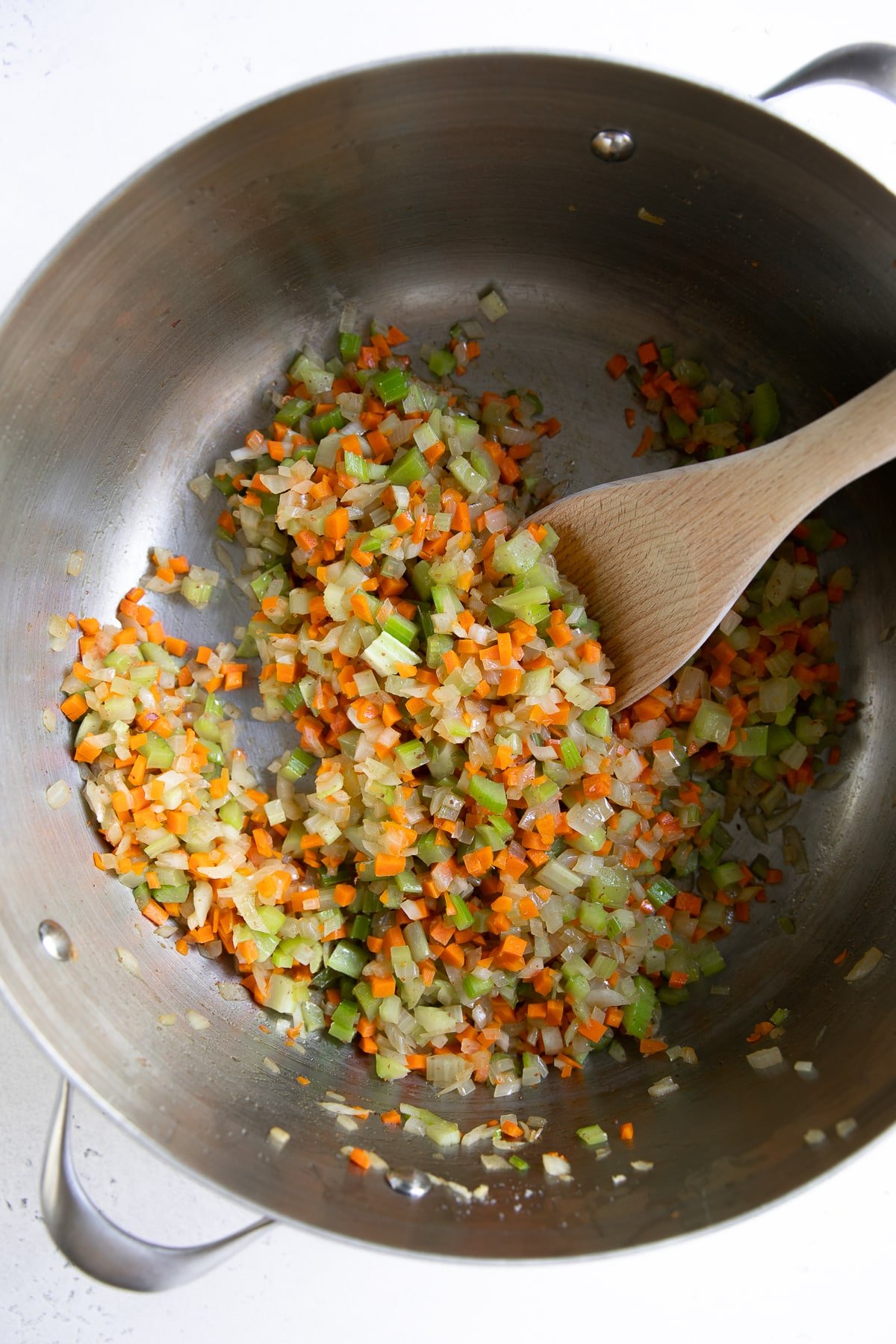 Large pot filled with finely minced onion, carrots, and celery cooking over low heat.