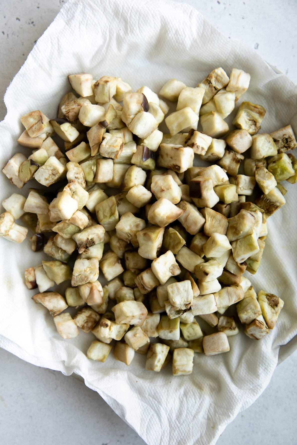 Microwaved cubes of eggplant on a plate lined with paper towels.