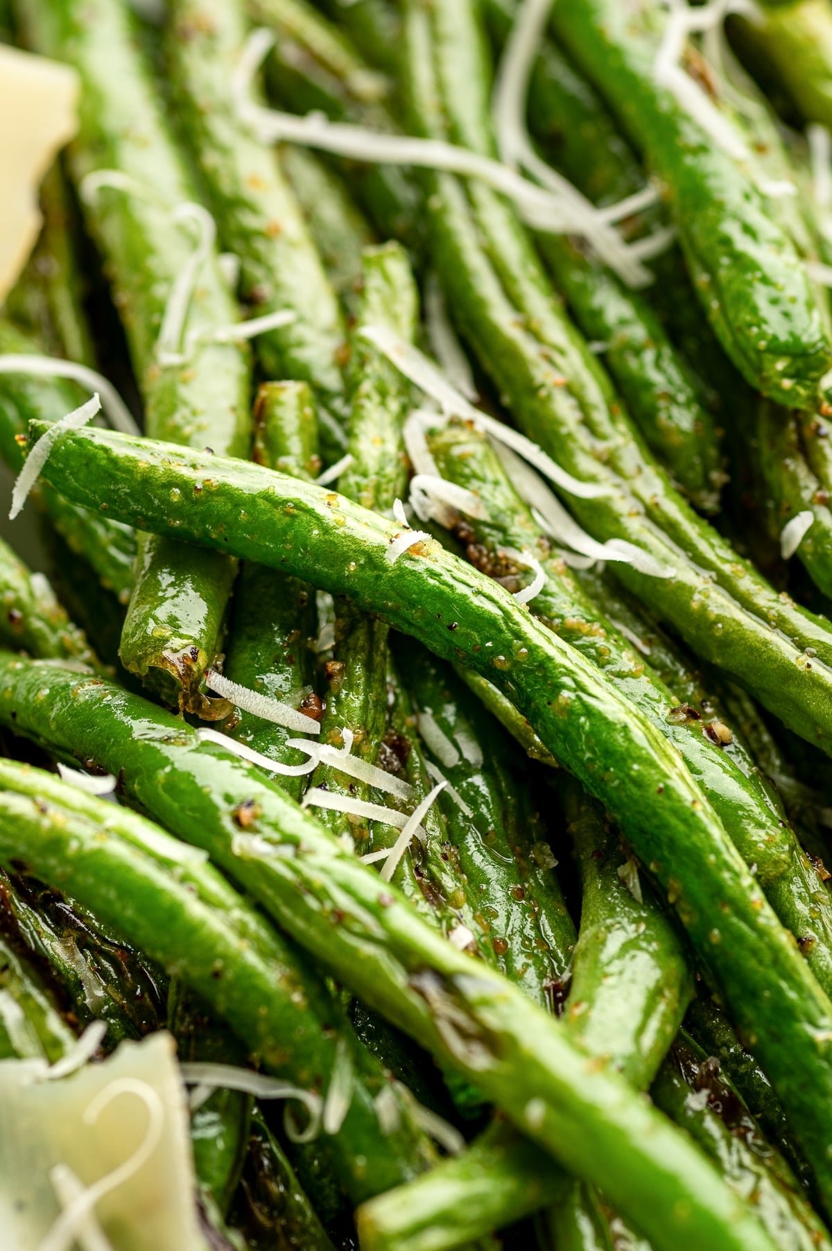 Close up of roasted green beans topped with shredded Parmesan cheese