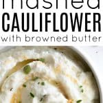 Bowl of creamy mashed cauliflower topped with swirls of browned butter and fresh herbs.