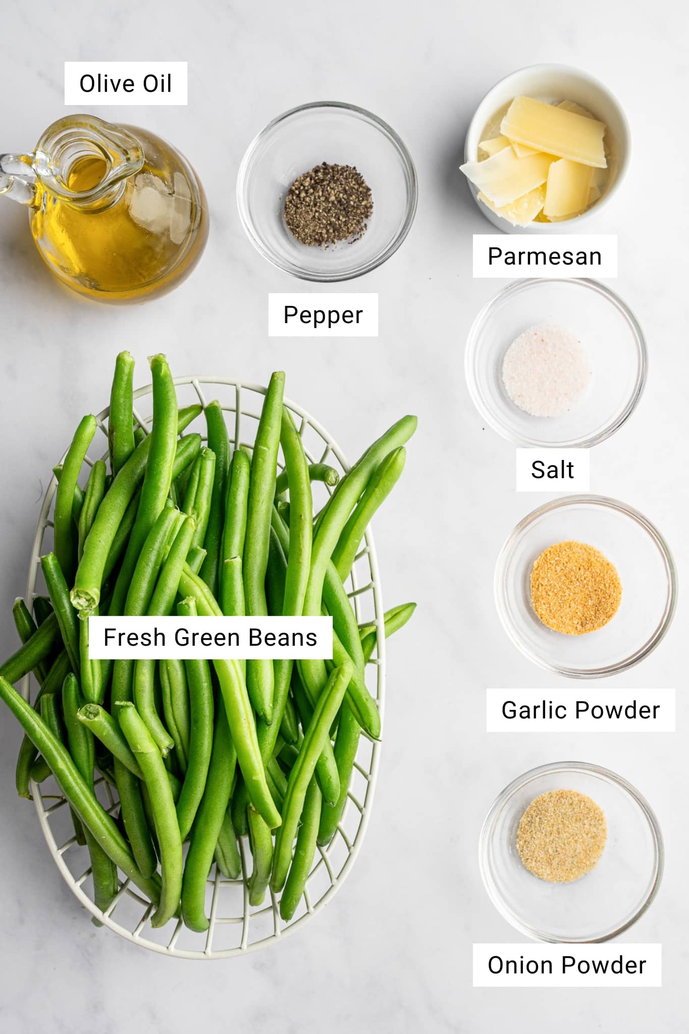 Overhead view of fresh green beans, olive oil, Parmesan, and seasonings for roasted green beans