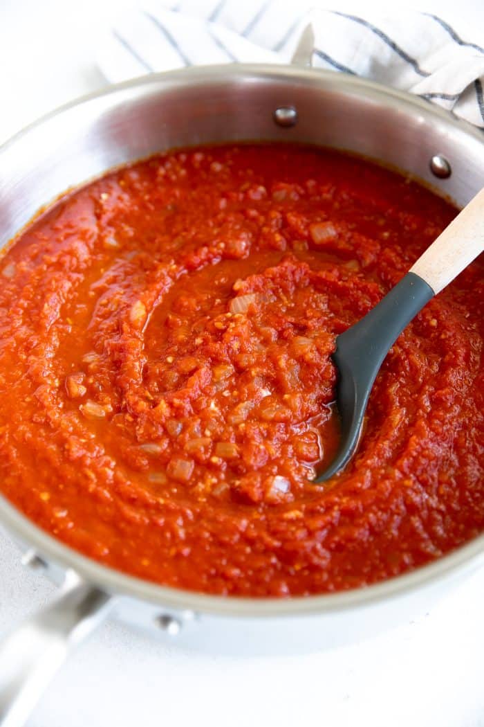 Ladle in a large shallow saucepan filled with Spicy Arrabbiata Sauce.