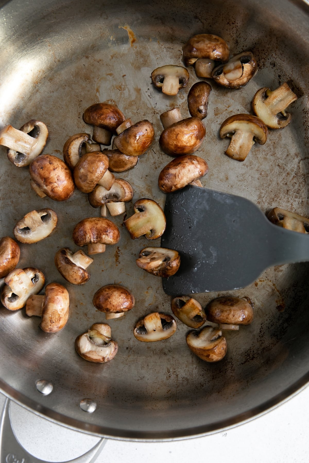 Crimini mushrooms saute in a large skillet.