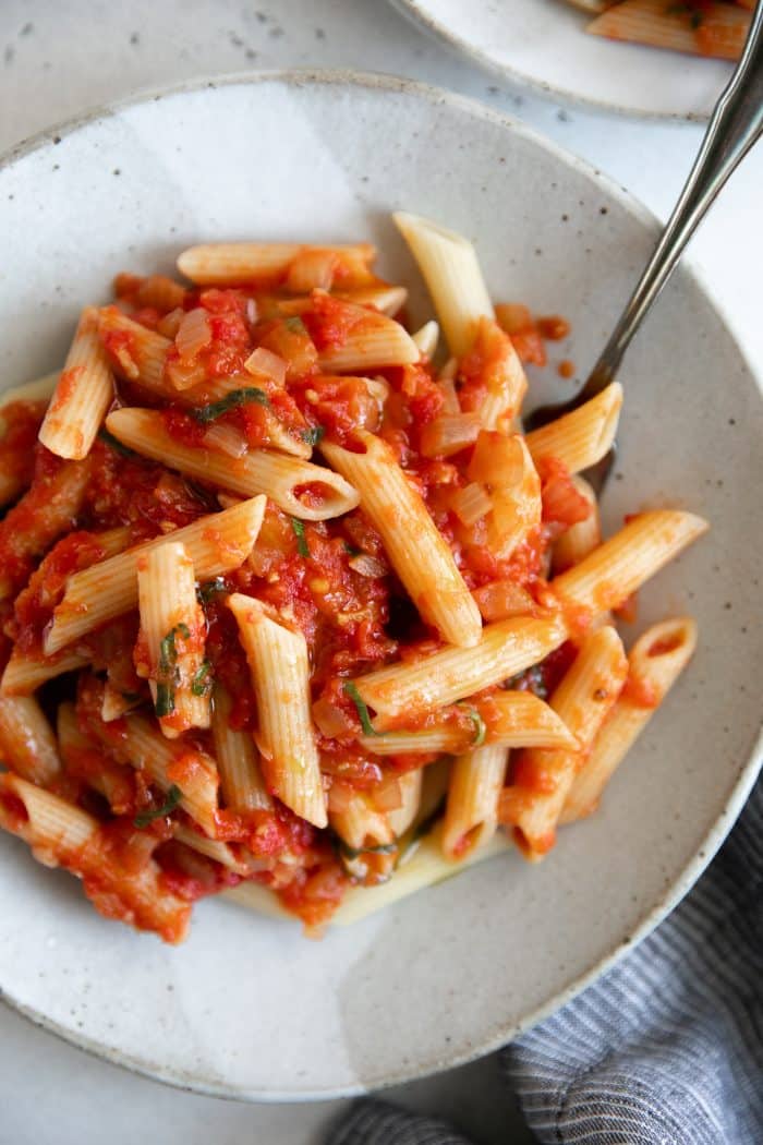 Small dinner plate filled with penne noodles tossed in homemade arrabbiata sauce.
