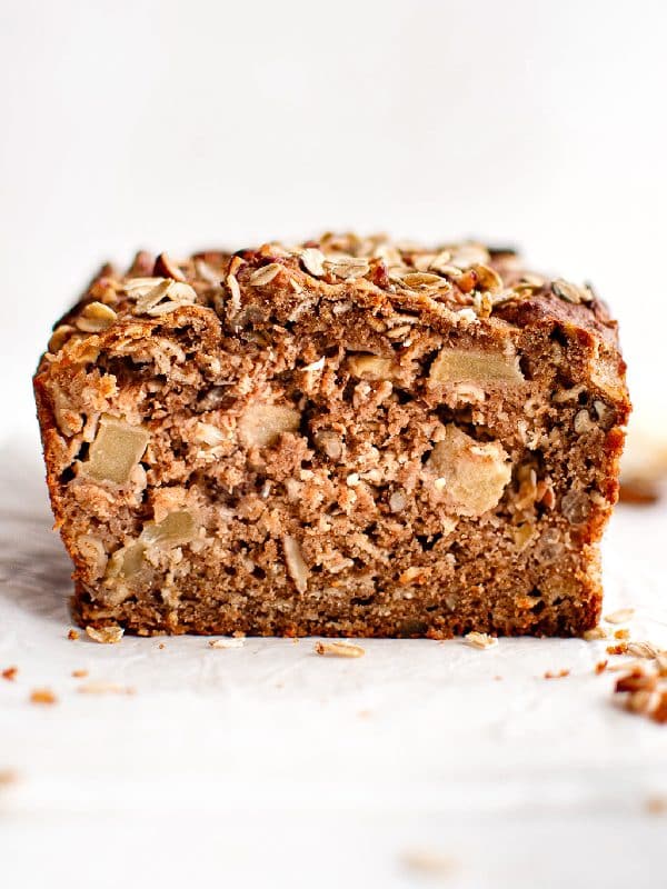Close-up cross-section of apple cinnamon bread showing a moist, tender interior filled with apple chunks, oats, and chopped nuts.
