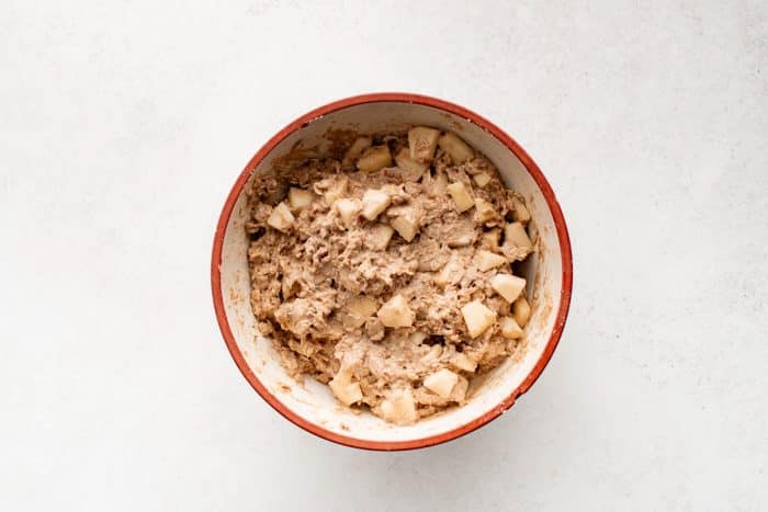 Overhead view of apple cinnamon bread batter with visible chunks of fresh apple and chopped pecans.