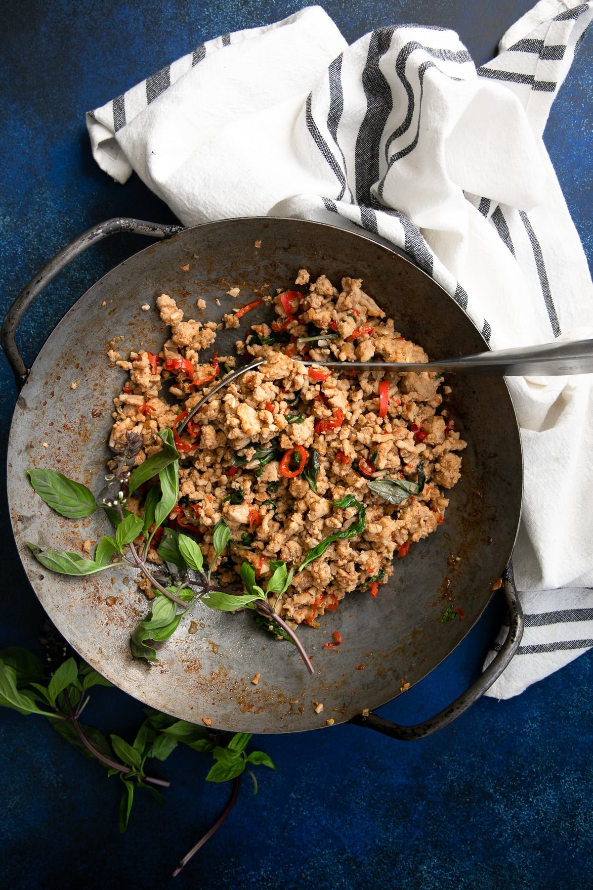 Large wok filled with cooked Thai Basil Chicken made with ground chicken cooked with thai basil, chilis, and different sauces.