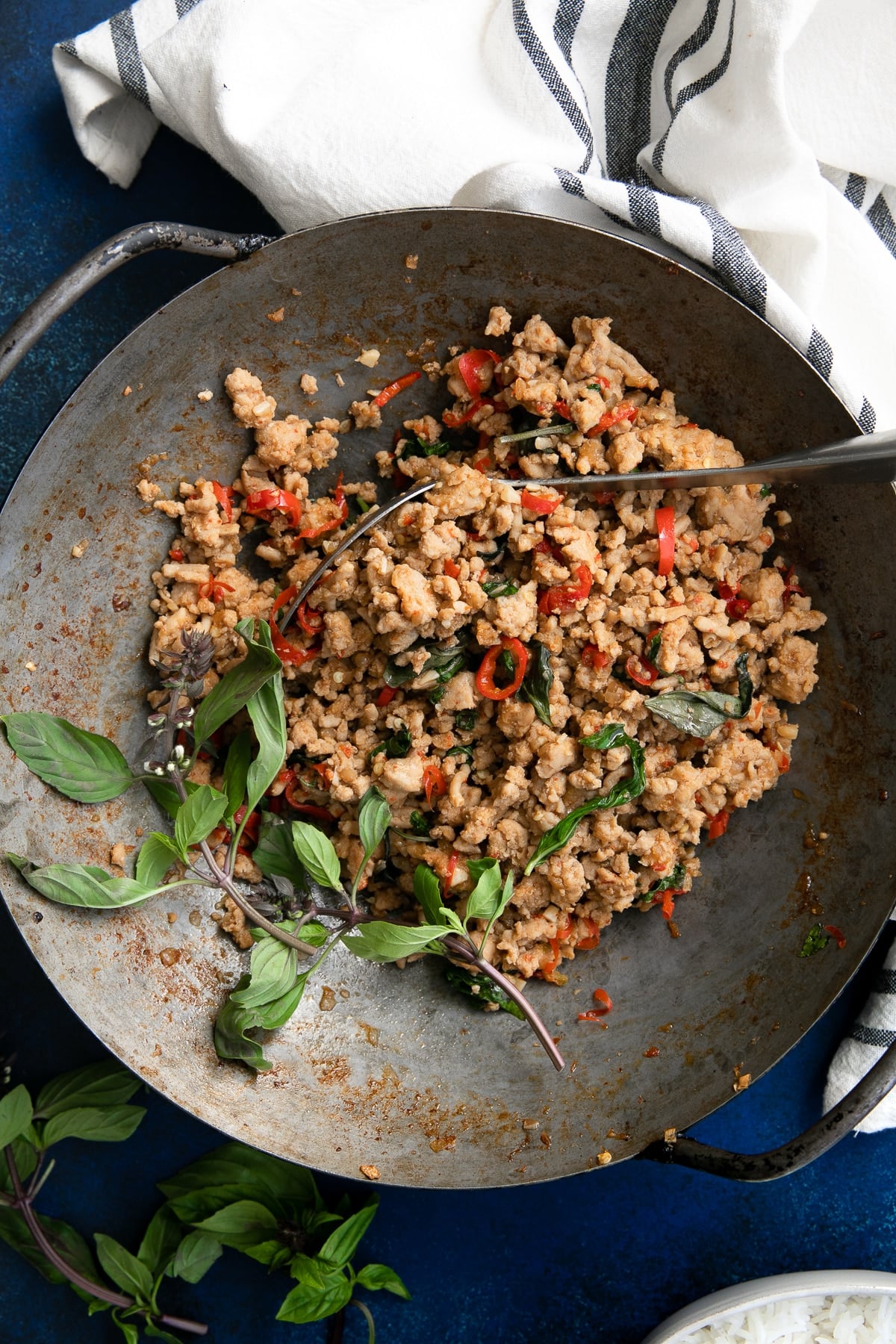 Large wok filled with cooked Thai Basil Chicken made with ground chicken cooked with thai basil, chilis, and different sauces.