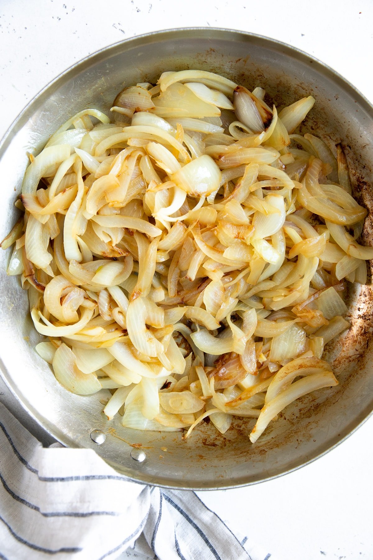 Softened, golden sliced yellow onions cooking in a medium skillet.