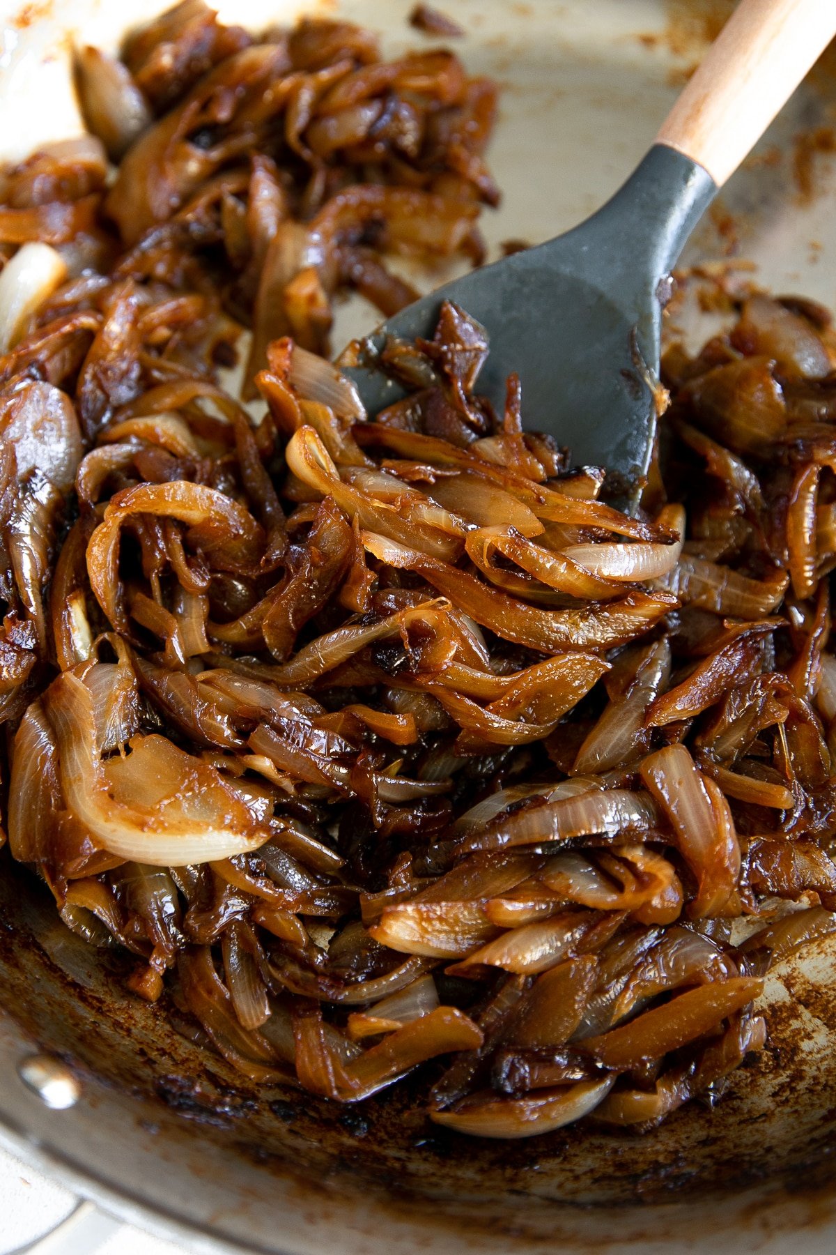 Close-up image of caramelized onions in a large stainless steel skillet.