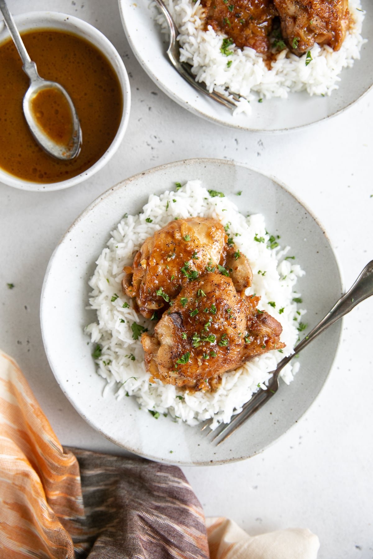 Two white plates filled with white rice and topped with chicken thighs cooked in a homemade honey mustard sauce in the Instant Pot.