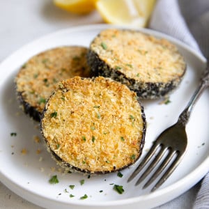 Small white plate with three slices of crispy baked eggplant.