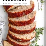 Vertical image of a sliced turkey meatloaf topped with a rich ketchup glaze and sprinkled with fresh herbs, with sprigs of thyme on the side.