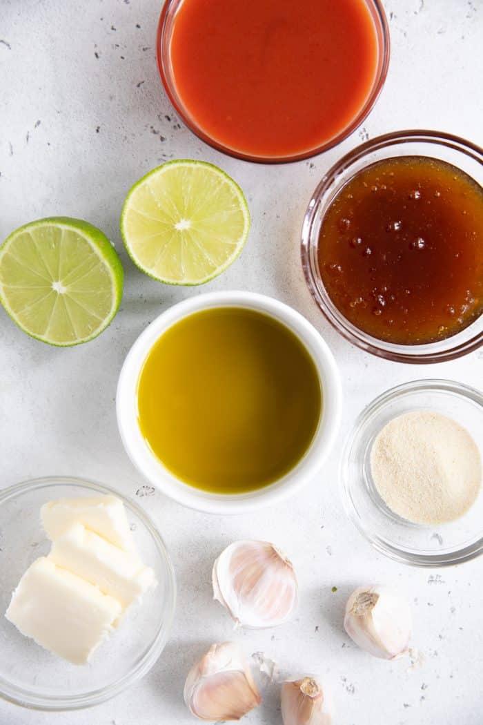 Ingredients needed to make homemade buffalo sauce including butter, garlic, onion powder, olive oil, lime juice, honey, and Frank's Red Hot Sauce.