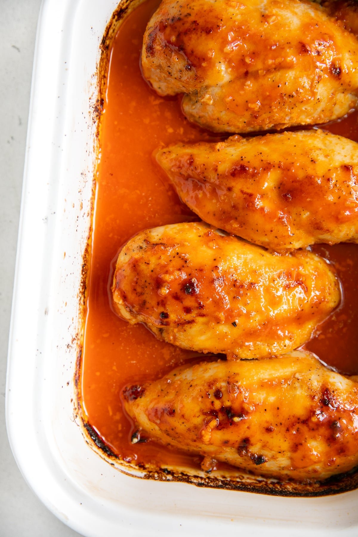Overhead image of four baked chicken breasts covered in buffalo sauce. Lazy keto meals.