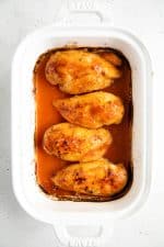Overhead image of four baked chicken breasts covered in buffalo sauce.