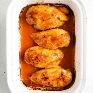 Overhead image of four baked chicken breasts covered in buffalo sauce.