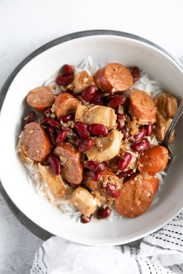 White bowl filled with spicy Cajun sausage, chicken, and red beans served over cooked white rice.