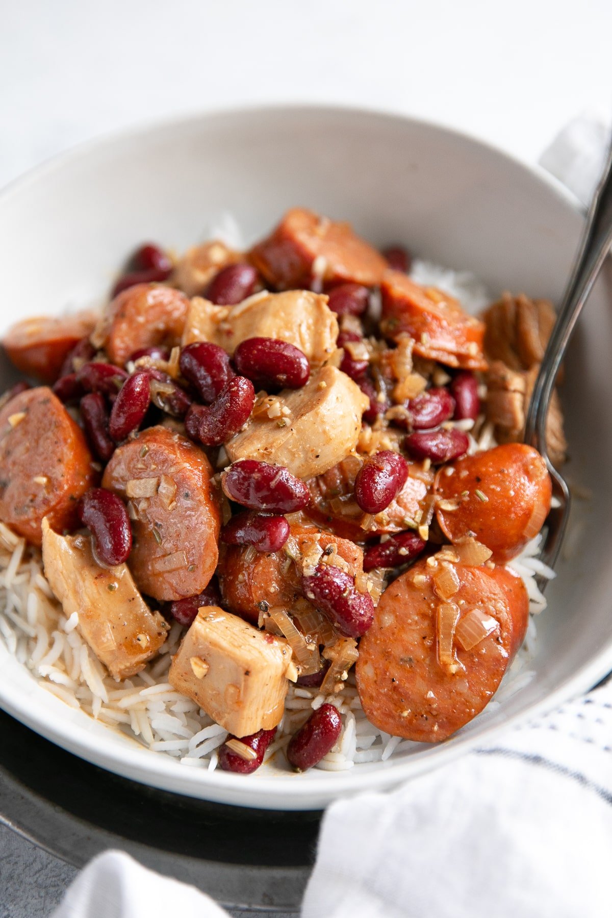 White bowl filled with spicy Cajun sausage, chicken, and red beans served over cooked white rice.