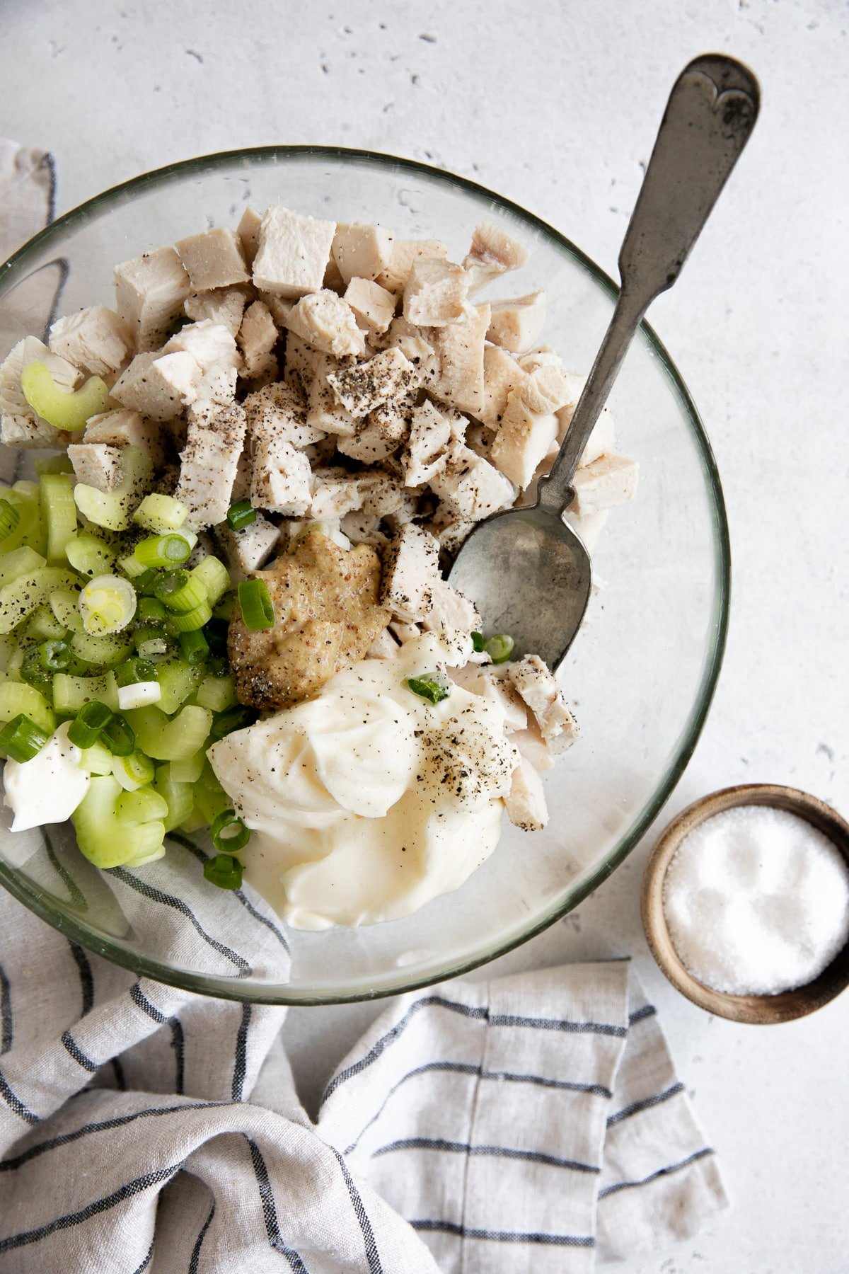 Chopped poached chicken, mayonnaise, brown mustard, celery, and green onions in a large glass mixing bowl.
