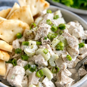 Prepared chicken salad recipe garnished with chopped green onions and served in a white serving bowl.