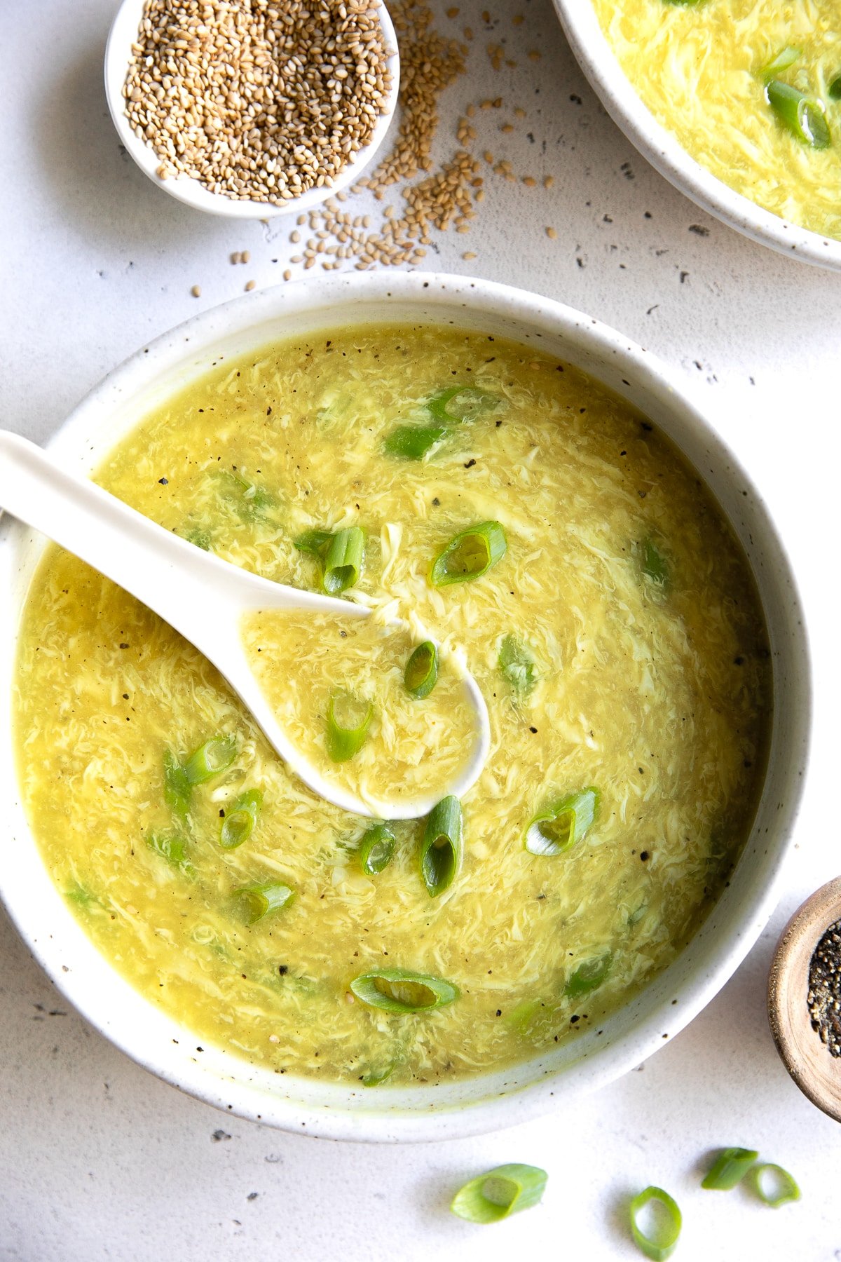 Large white shallow bowl filled with easy egg drop soup recipe garnished with sliced green onions.