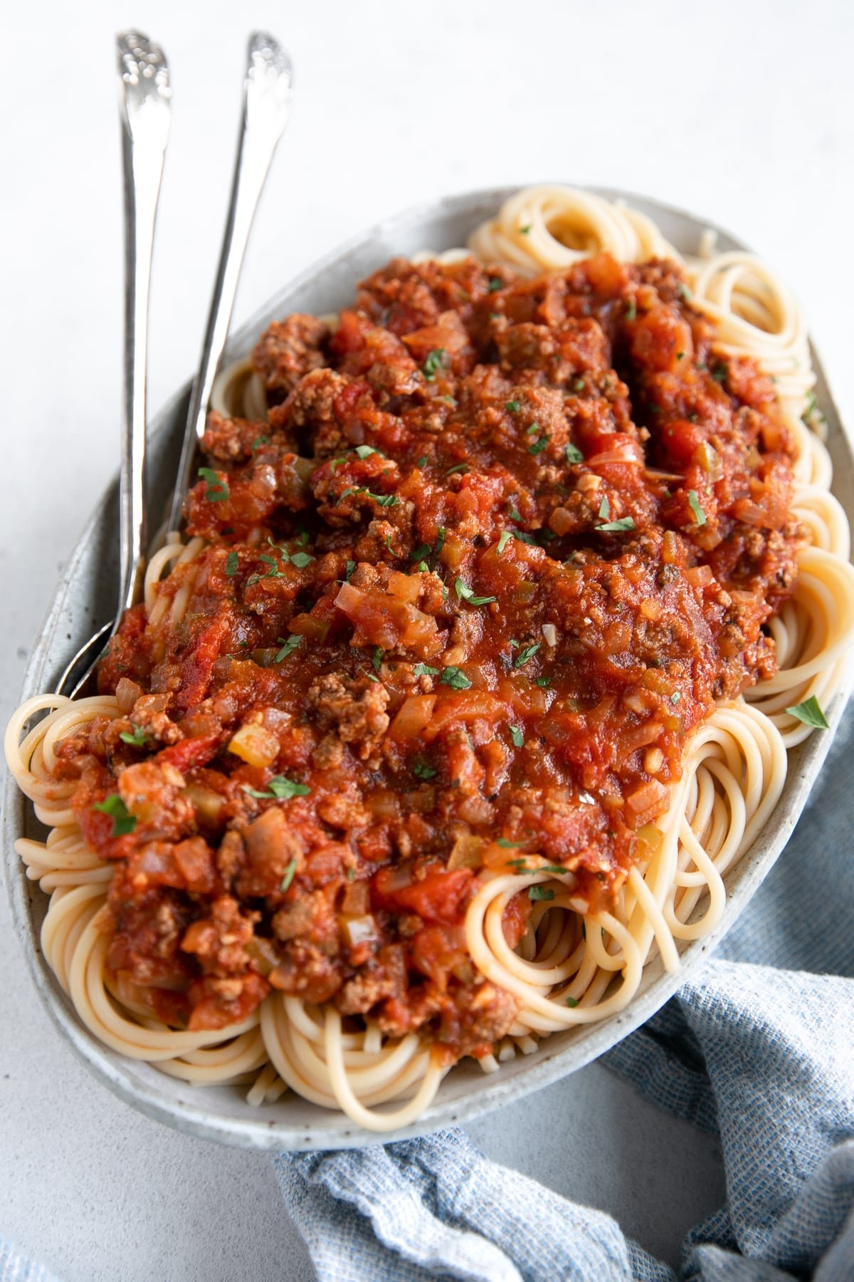 Large white serving plate filled with spaghetti noodles topped with homemade spaghetti sauce recipe.